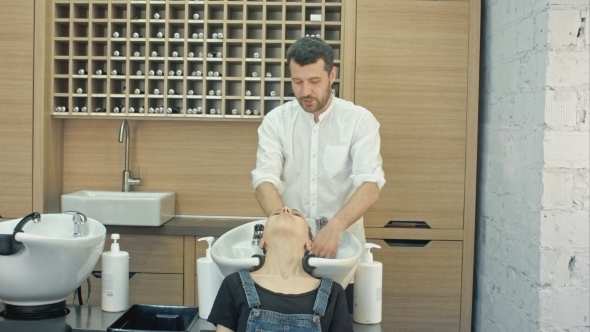 Handsome Hairdresser Washing Female Hair With Concentration