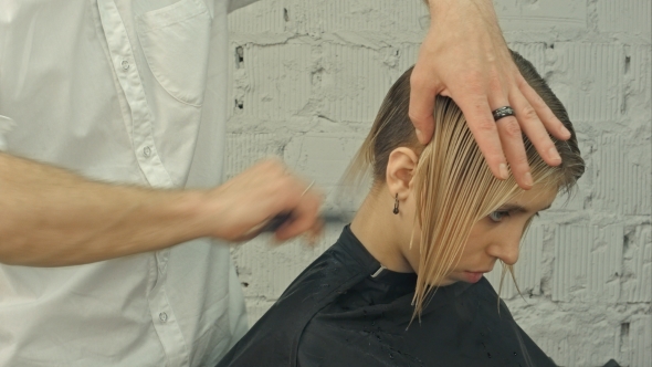 Smiling Client Sitting In a Hair Salon While Hairdresser Is Combing Her Hair