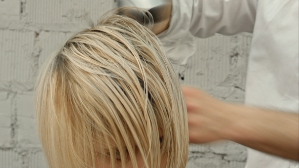 Hairdresser Drying Woman's Hair Using Hair Dryer