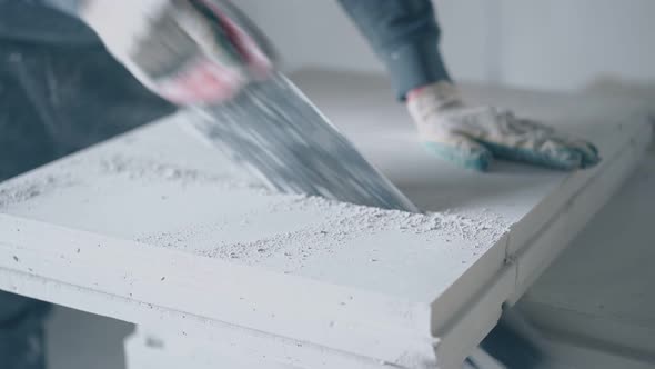 Worker in Gloves Holds Big Saw and Cuts Grey Board on Stand