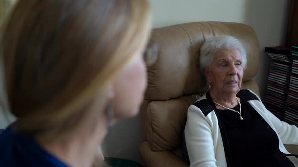 From the perspective of a blonde woman, a pretty, gray haired elderly woman holds a conversation.