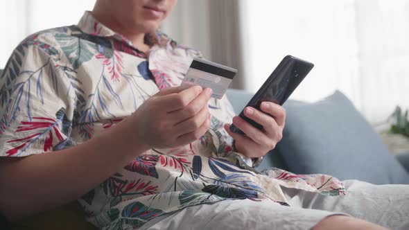 Close Up Of Hand Holding Credit Card And Using Smartphone Shopping Online In Living Room