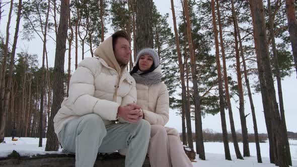 Couple in Love Sitting on a Log in the Forest