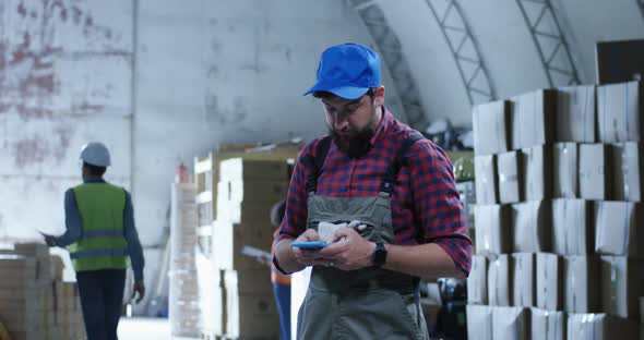 Worker Using Phone in a Warehouse