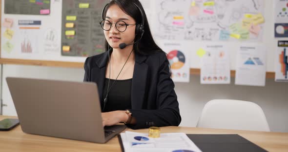 Happy female glasses wears headset video calling on laptop