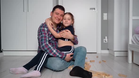 Father and daughter. They look at the camera and smile. Positive emotions after the board game