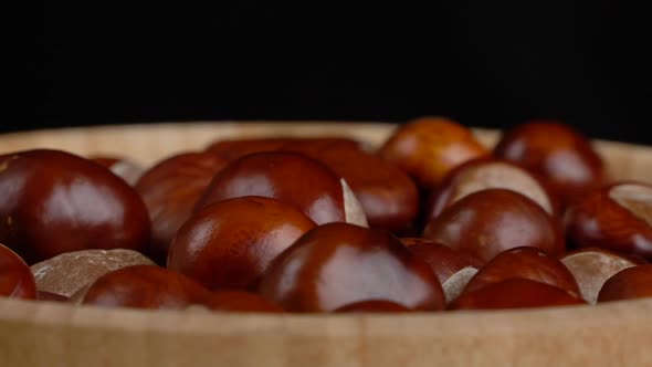 Chestnuts in a Wooden Bowl Rotate on Black Background