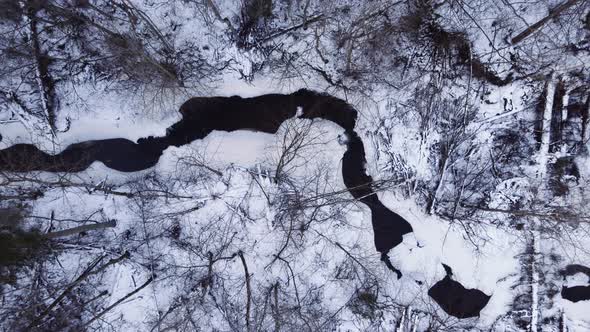 winding stream in the winter forest top view. Small river in the mountains.