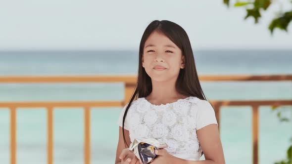 Philippine Schoolgirl in White Dress Smiles Eating Crispy Potato Chips