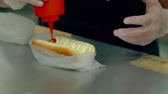 CU Slow Motion Cook Prepares a Hot Dog Pours a Red Ketchup on a Loaf