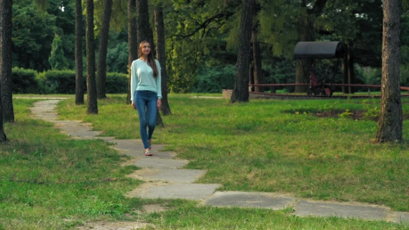 Young Brunette Girl Is On a Path In a Park And Glances Up.