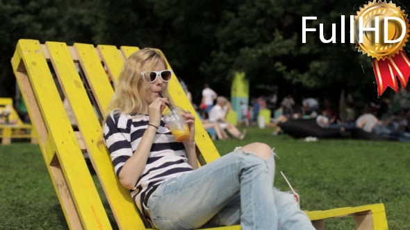 Girl Drinks Fruit Juice Sitting on a Lounger