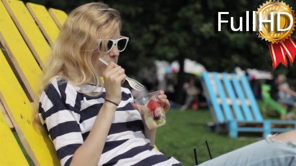 Girl Eating Fresh Fruit Sitting on a Lounger