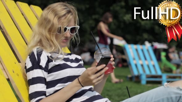 Girl With Phone and Juice Resting on a Wooden