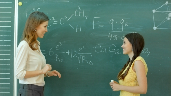 Pretty Young Female College Student Writing On The Chalkboard Blackboard During a Chemistry Class