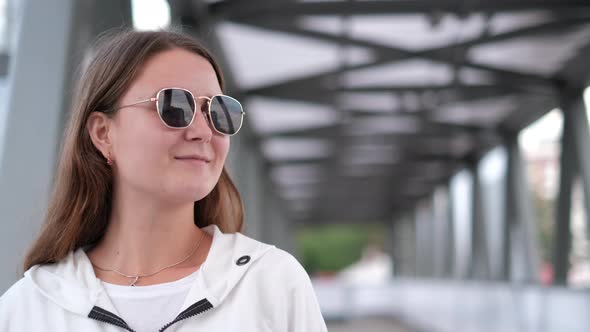 One brunette girl in sunglasses looks at the camera and laughs