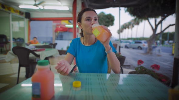 Woman Drinking Glass Of Orange Juice Sitting At a Restaurant