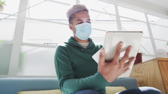 Man wearing face mask wiping his digital tablet with a tissue