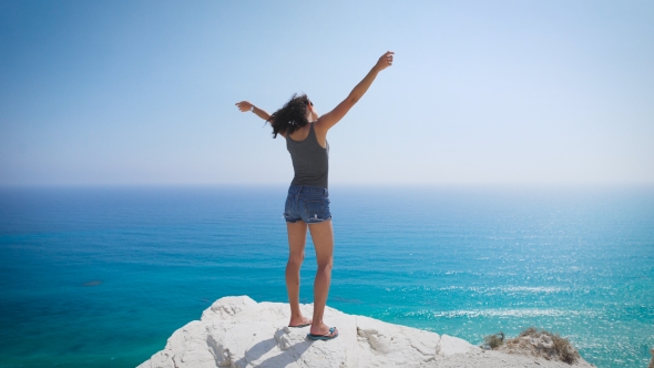 A Young Woman Standing By The Sea. Enjoying The Fresh Air