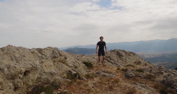 Boy walks on rocky ridge in the mountains