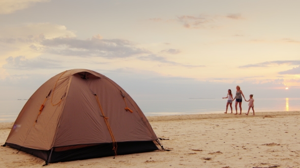 A Woman With Her Two Daughters Walking Along The Seashore, In The Foreground Is a Tent For The Night