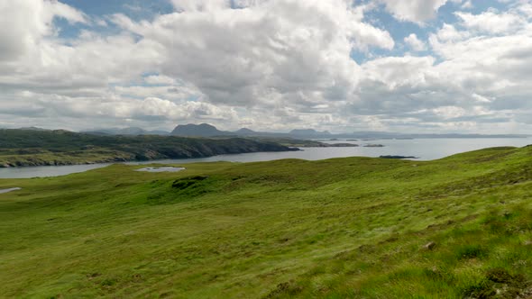 A wide panning landscape view of the mountains (suilven) and rocky coastline of North Scotland (Suth