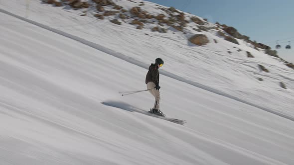 Woman Skiing Down Hill As Cable Cars Pass Overhead