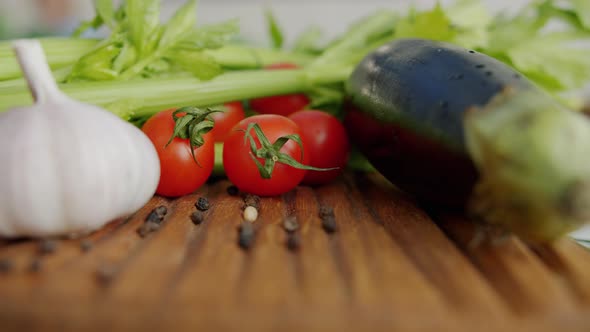 Ripe Tomatoes, Celery, Eggplants and Garlic on Wooden Chopping Board in Kitchen