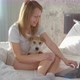 A beautiful girl in casual clothes uses a laptop on the bed - VideoHive Item for Sale