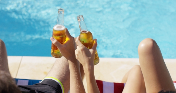 Couple Relaxing At The Pool With Beers