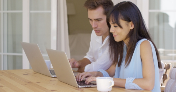 Couple Working On Laptop Computers Together