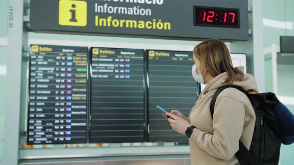 Woman Watching Arrival Board and Checking Flight