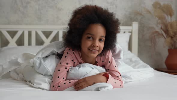 Portrait Little African American Girl Lying Under Covers Looking at Camera and Smiling