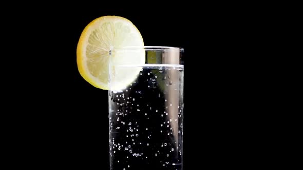 Close Up of Glass of Sparkling Soda Water With a Lemon Wedge Black Background