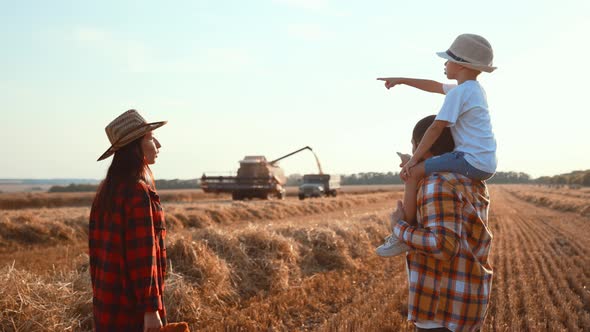 Rear View of Family Together Walk in Wheat Field with Haystacks Made with Straw