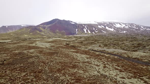 Aerial Shot of Beautiful Snowy Mountain Peak and Immense Land Covered In Moss