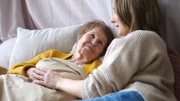 Granddaughter Supporting And Cheering Ill Grandmother In Bed Holding Her Hand