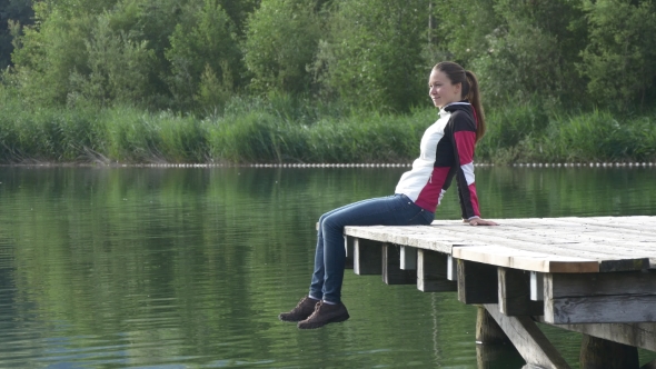 Relaxed Woman Sits On The Pier