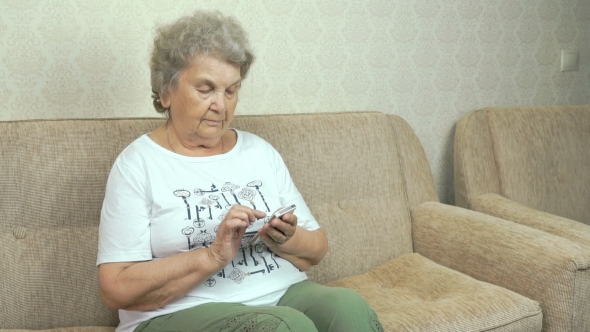 Old Granny Holding a Mobile Phone At Home