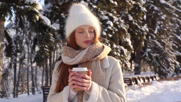 Portrait of Pretty Young Woman in Warm Clothes Drinking Hot Coffee From Cup Outdoors in Sunny Winter