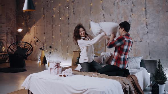 Couple Sitting on Bed Having Fun with Pillows in Bedroom.