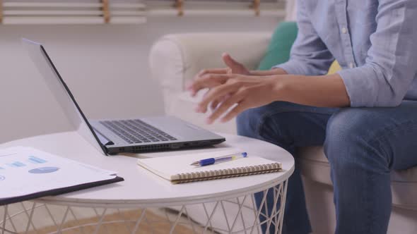 At home, an Asian businessman works on a desk with a laptop, searching for jobs and paperwork.