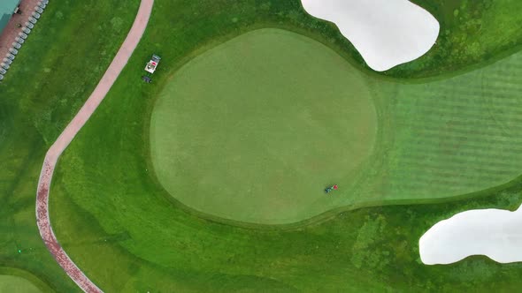 Birds eye view of a golf course. Hole near the clubhouse. Early morning shot of a worker mowing and