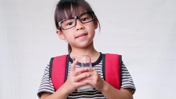 Cute schoolgirl drinking milk from a glass before going to school. Healthy nutrition for children. alt