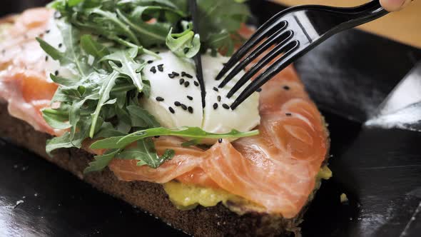 Person Hands Cut Bread with Salmon Egg with Knife and Fork