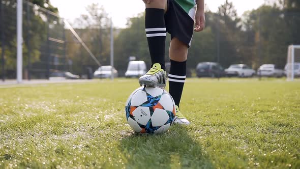 Boy Legs on the Soccer Ball on the Football Background