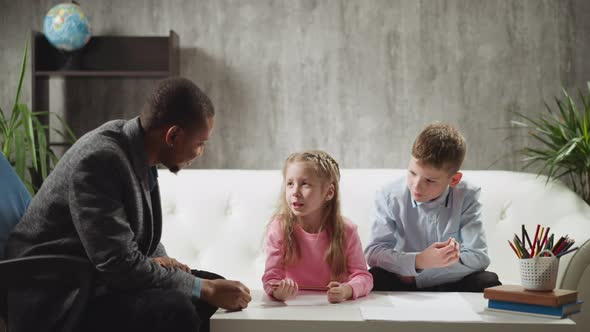 Little Girl Answers Nodding Tutor Classmate Sits on Sofa