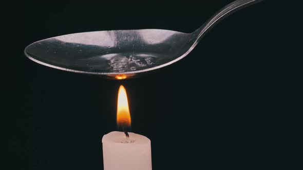 Preparing a Dose of Heroin in a Spoon Over a Candle Flame