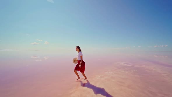 Happy Woman in Red Skirt Running Enjoying Bright Pink Salt Lake with Blue Sky