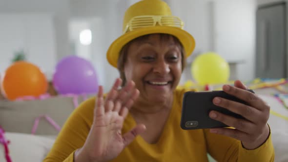 Happy african american senior woman making new year's eve smartphone video call blowing kisses